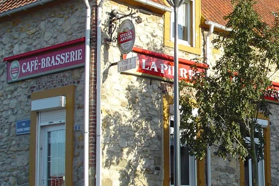 Façade en pierre de la Brasserie La Pierre, avec ses enseignes rouges, rue Gambetta à Wissant